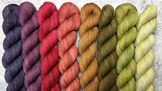 Set of colorful yarn skeins with labels on a gray background